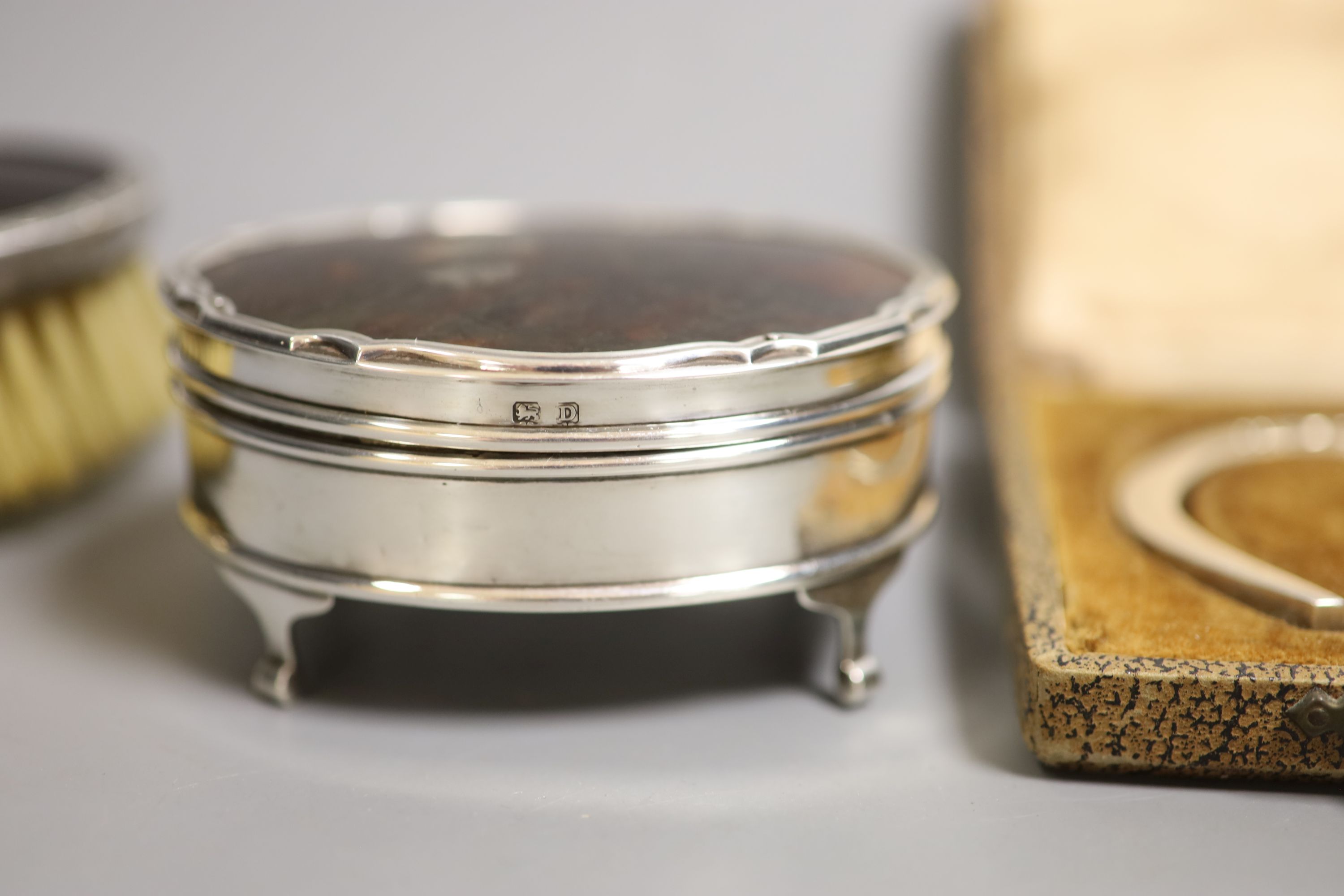 A George V silver and tortoiseshell mounted trinket box, brushes, horseshoe and brooch.